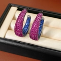 Makroaufnahme von C-förmigen Ohrringen mit pinken und blauen Kristallen auf einer Box - Gewehrschwarz-Violett-Blau (Mit 925 Silberstift)