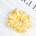 Glossy bright yellow satin scrunchie with soft pleated texture on Vogue magazine - Yellow