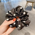 Polka dot satin scrunchie in black and white held by hand for a stylish hair accessory - Black Polka Dot