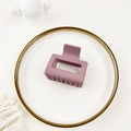 Detail of matte dark purple rectangular hair claw clip displayed on an elegant white plate - Pink Purple