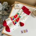 Calze natalizie rosse e verdi festive con motivi di alce e Babbo Natale su una scrivania - Taglia unica / Bianco