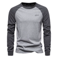 Detail van grijze raglanmouw stiksels en AIOPESON borduursel op een katoenen t-shirt - S / Lichtgrijs