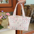 Borsa tote trapuntata con fiocchi rosa e fiori in morbido cotone tenuta in mano - Patchwork bacca