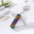 Detail of rainbow rhinestone perfume bottle keychain on white stone with white roses - Gradient Color 2