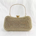 Detailaufnahme einer goldenen Abendtasche mit vollem Straßbesatz und rundem Metallgriff - Gold