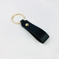 Minimalist black PU leather keychain with gold metal ring and rivet on a textured surface - No.1 Black
