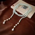 Detail view of multi-layer long pearl necklace with golden clasp on vintage book - Long Multi-layer Tassel Style / White
