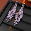 Vue macro détaillée de boucles d'oreilles à pampilles en strass violets dans un coffret - Style Losange Violet