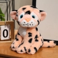 Pink leopard plush toy with blue eyes in sitting pose on a wooden desk setting - 17cm / Pink With Black Spots