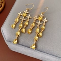 Dettaglio di orecchini a stella e cuore in oro con cristalli gialli su velluto grigio - Giallo