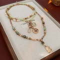Detail of layered vintage tiger eye bead necklaces with golden charms in a jewelry box - Green