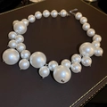 Detail of irregular white pearls on a dark leather surface with a silver metallic clasp - White Irregular Baroque Pearl Necklace