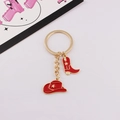 Close-up of golden keychain with red enamel cowboy hat and star-patterned boot charms - 3 Red - Gold Ring / Red