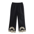 Detailed close-up of black pants featuring white floral embroidery on the cuffs - S / Bottoms / Black