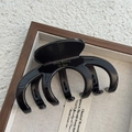 Detailopname van grote zwarte glanzende haarklem met gouden letters op een display plateau - Ongeveer 9cm Lang / Glanzend Zwart (4+3 Klem)