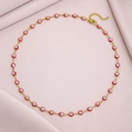 Detailed view of evil eye necklace with red charms and golden lobster clasp on pink fabric - Red