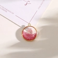 Round golden resin pendant featuring a pink dried flower and shimmering glitter detail - Style 11