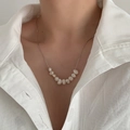 Close-up of minimalist silver necklace featuring white baroque pearls on a model's neck - Silver - Natural Pearl