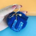 Close-up of blue pompom keychain with letter U sequin pendant and matching tassel - Letter U