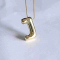 Macro detail of puffy letter J pendant in gold finish with a polished box chain necklace - Letter J