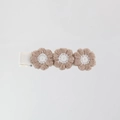 Close-up of three knitted beige flower petals on a white ribbon-wrapped hair clip - Beige Brown