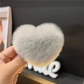 Close-up of a soft grey heart-shaped faux rabbit fur hair claw clip held in hand - Gray