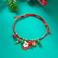 Detail of red braided Christmas bracelet with Santa and candy cane charms on green background - Santa Claus/Candy Cane/Gift Box/Red Green Bead