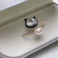 Golden twisted ring featuring a black cat shell motif and a white teardrop pearl - Black Cat Shell