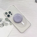 Dettaglio del supporto MagSafe circolare viola fissato sul retro di un iPhone bianco - Staffa Magnetica Base Opaca / Grigio