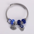 Detail of twisted silver bracelet with blue evil eye beads and Hamsa hand charm - Blue