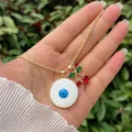 Detailansicht der 18K vergoldeten Evil Eye und roten Kirsch-Anhänger an einer Kordelkette - Evil Eye & Kirsche - Feine Kette