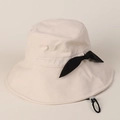 Detailed macro shot of cotton linen sun hat fabric with black bow and windproof chin strap - Beige