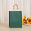 Detail of dark green kraft paper gift bag with twisted handles in a cozy home setting - Dark Green