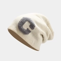 Detailopname van de grijze bouclé geborduurde letter C op een crème gebreide muts - M (56-58cm) / Wit