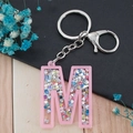 Pink acrylic letter M keychain with colorful glitter sequins and silver metal clasp - Letter M