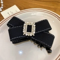 Barrette à nœud en tissu noir élégante avec strass brillants sur une assiette blanche - Pince Torsadée / Noir