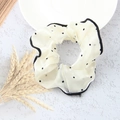 Chouchou en soie blanc cassé à pois noirs et bordure sur une table blanche - Pois