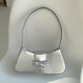 Minimalistische silberne Schultertasche mit Metallic-Finish und Schleife auf Stuhl - Silber