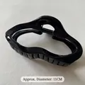 Detail view of 11cm black glossy hair claw clip with a wavy design on white leather - Bright Black