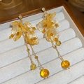 Dettaglio di orecchini a fiore in resina ambra con catena dorata e piccoli cristalli - Nappa a Fiore Lunga / Giallo Ambra (Perno in Argento)