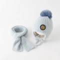 Detail von hellblauem Plüsch-Mützen-Schal-Set mit Pelzbommel und weichem M-Aufnäher - Blau