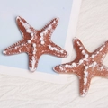 Macro detail of two resin starfish ornaments with white dots on a blue and white background - Light Coffee Starfish
