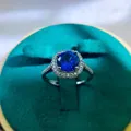 Macro shot of a halo ring featuring a round blue sapphire with white gemstone accents - A3 Open Type / Blue