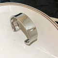 Vista detallada de un brazalete ancho y abierto en plata pulida sobre un plato cerámico - Brazalete - Plata