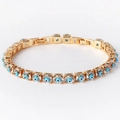 Bracelet chaîne en cuivre doré avec zircons et breloques œil bleu sur fond blanc épuré - Zircon Bleu Clair