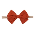 Detailed view of the orange textured fabric bow on a soft nude nylon baby headband - Orange