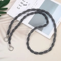 Close-up of a dark grey braided crossbody phone strap with silver ring clasps on a magazine - Black
