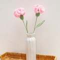 Two handmade crochet pink carnations in a white ceramic vase inside a woven basket - Carnation (Single Finished) / Pink (Long Leaf)