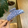 Close-up of blue and pink mosaic star pattern hair claw clip in a hand-held view - Large / Clear Purple Star