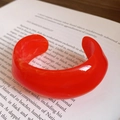 Retro orange acrylic chunky open cuff bracelet with glossy finish on a book background - Bold Style Open Bangle / Orange